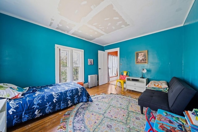 bedroom featuring wood finished floors, ornamental molding, and radiator heating unit