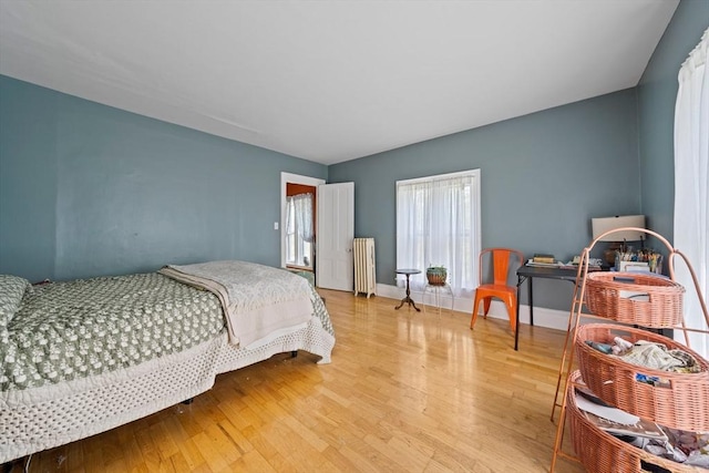bedroom featuring light wood-style floors, baseboards, and radiator heating unit