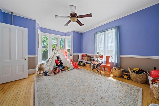 rec room with wood-type flooring, a ceiling fan, and crown molding