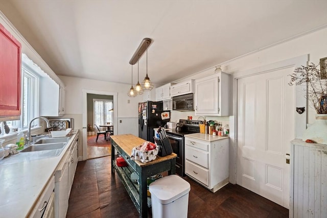kitchen featuring hanging light fixtures, a sink, light countertops, black appliances, and white cabinetry
