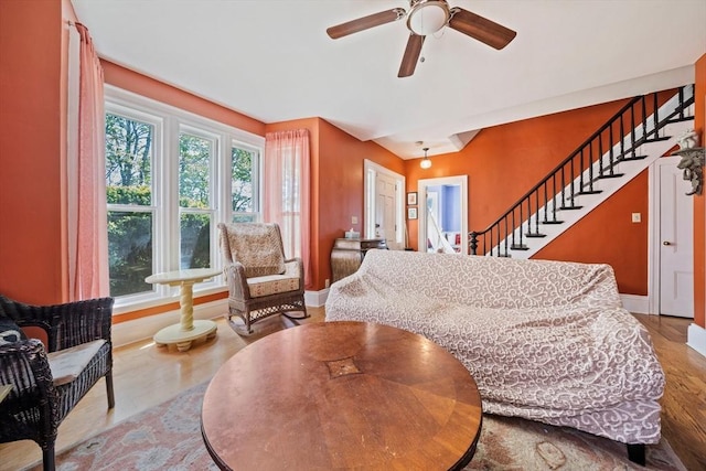 living room featuring baseboards, ceiling fan, wood finished floors, and stairway