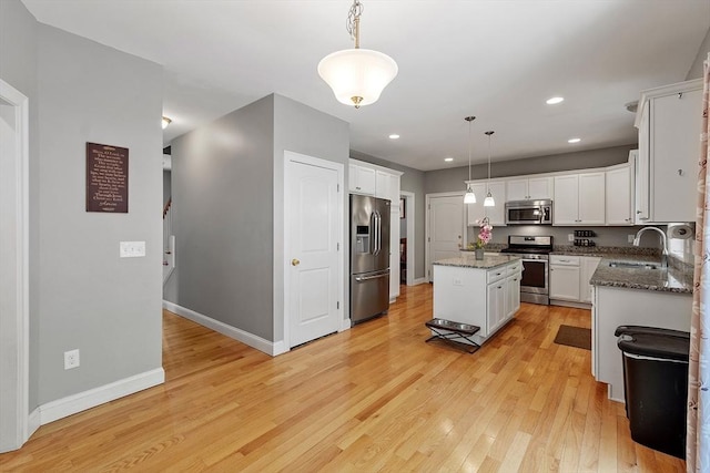 131 Great Rd, Shirley, MA 01464 - kitchen featuring stainless steel appliances, a center island, light wood finished floors, stone countertops, and white cabinetry