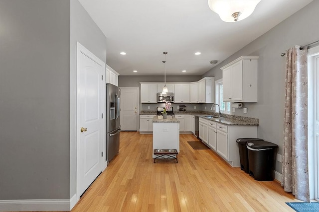 131 Great Rd, Shirley, MA 01464 - kitchen with stainless steel appliances, light wood-type flooring, a center island, white cabinetry, and light stone countertops