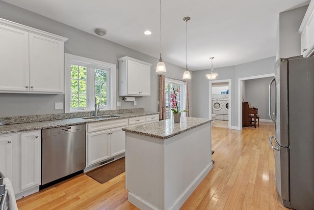 131 Great Rd, Shirley, MA 01464 - kitchen with appliances with stainless steel finishes, washer and clothes dryer, white cabinets, a center island, and light wood-style flooring
