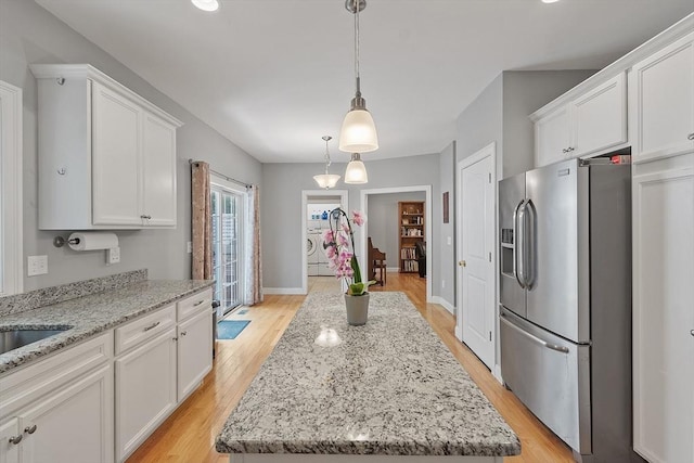 131 Great Rd, Shirley, MA 01464 - kitchen featuring stainless steel refrigerator with ice dispenser, independent washer and dryer, white cabinets, light wood-style flooring, and a kitchen island