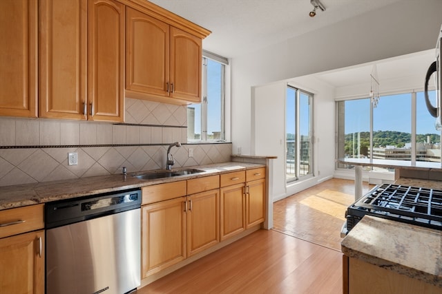 kitchen with dishwasher, range, sink, light hardwood / wood-style flooring, and backsplash