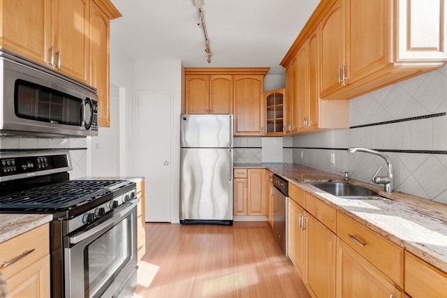 kitchen with light stone counters, sink, tasteful backsplash, light hardwood / wood-style flooring, and stainless steel appliances