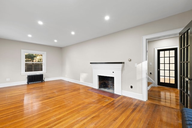 unfurnished living room with wood-type flooring and radiator heating unit