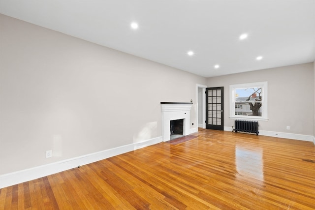 unfurnished living room featuring light hardwood / wood-style floors and radiator heating unit