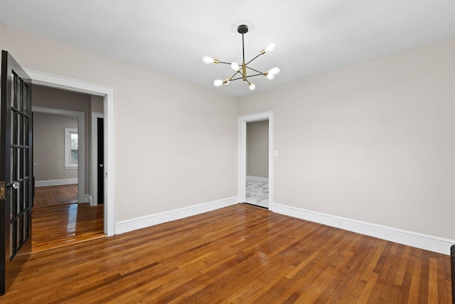 spare room with dark hardwood / wood-style floors and a notable chandelier