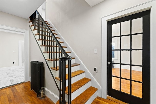 stairs with hardwood / wood-style floors and radiator