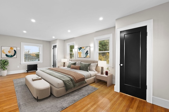 bedroom featuring multiple windows, radiator, and light hardwood / wood-style flooring