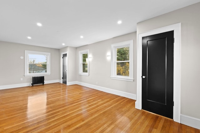 unfurnished living room featuring a healthy amount of sunlight, light wood-type flooring, and radiator