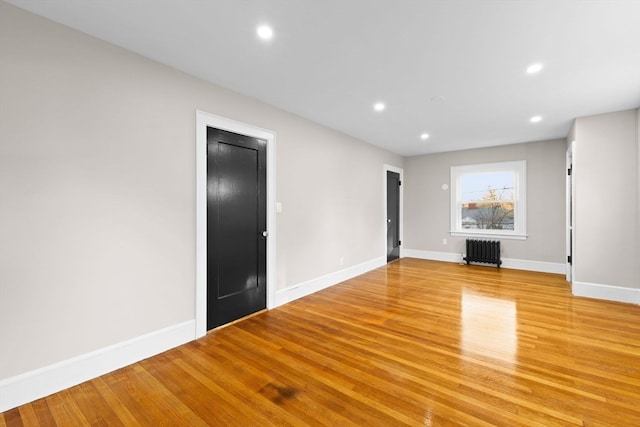 unfurnished living room featuring radiator heating unit and light hardwood / wood-style floors