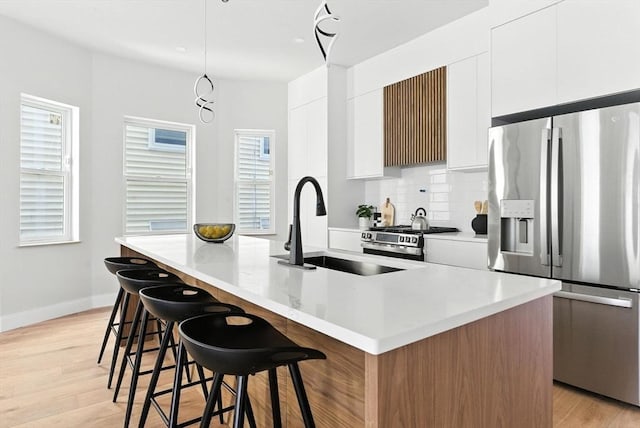 34 Woodford St Unit 2, Boston, MA 02125 - kitchen with appliances with stainless steel finishes, white cabinetry, tasteful backsplash, an island with sink, and a kitchen bar