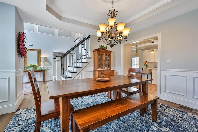 dining room featuring wood-type flooring, a tray ceiling, crown molding, and a chandelier