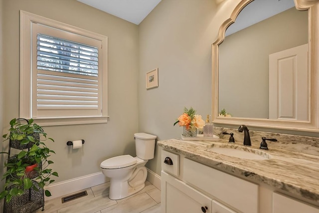 bathroom with toilet, vanity, and tile patterned floors