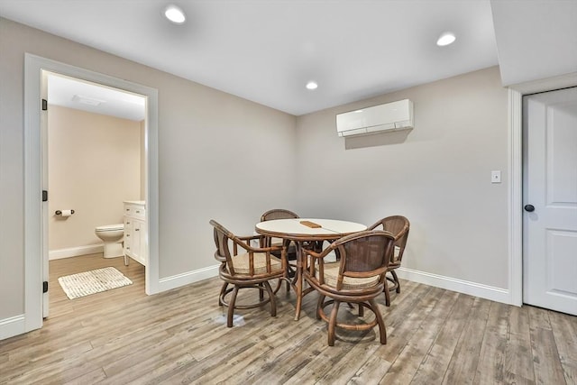 dining space with light wood-type flooring and an AC wall unit