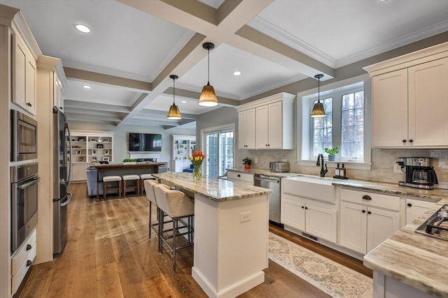 kitchen with light stone counters, appliances with stainless steel finishes, a center island, and coffered ceiling