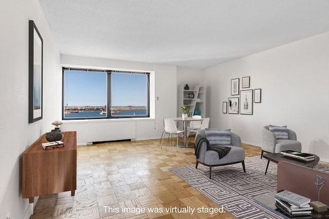 sitting room with light parquet flooring, a water view, and radiator