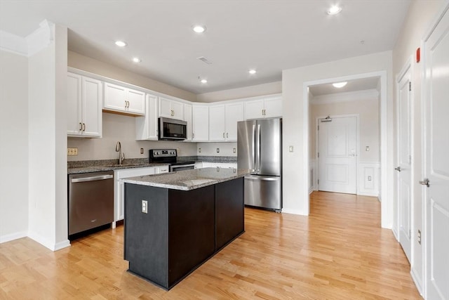 kitchen with sink, light stone countertops, a kitchen island, white cabinetry, and stainless steel appliances