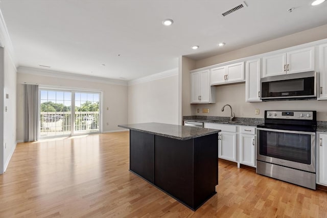 kitchen with white cabinetry, sink, dark stone counters, a kitchen island, and appliances with stainless steel finishes