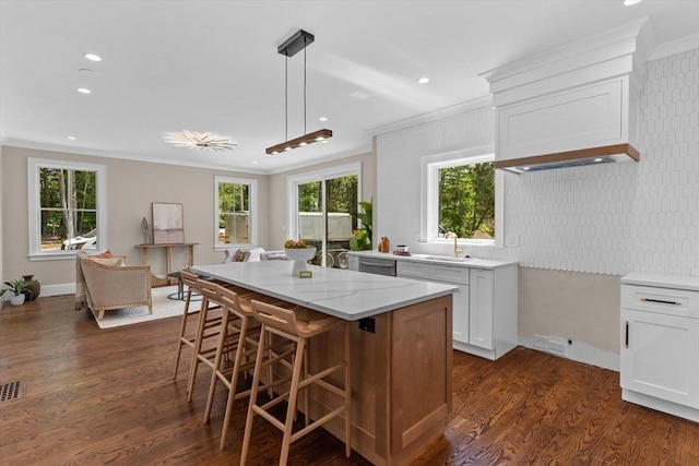 1780 Central Ave, Needham, MA 02492 - kitchen featuring ornamental molding, a kitchen bar, light stone counters, dark wood-style flooring, and a center island