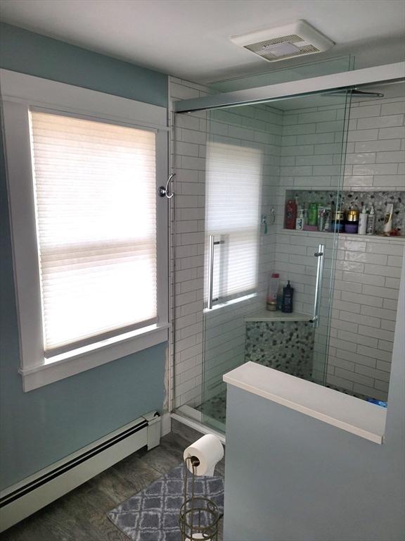 full bathroom with a baseboard radiator, visible vents, a wealth of natural light, and a shower stall