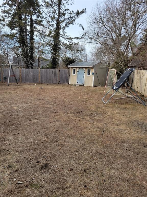 view of yard featuring a storage shed, a fenced backyard, and an outbuilding