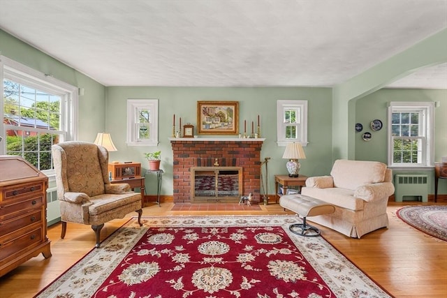 52 Harding Rd, Lexington, MA 02420 - living room with radiator heating unit, wood finished floors, a brick fireplace, and baseboards