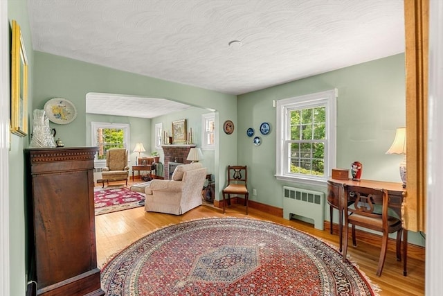 52 Harding Rd, Lexington, MA 02420 - living room featuring radiator heating unit, wood finished floors, healthy amount of natural light, and a textured ceiling