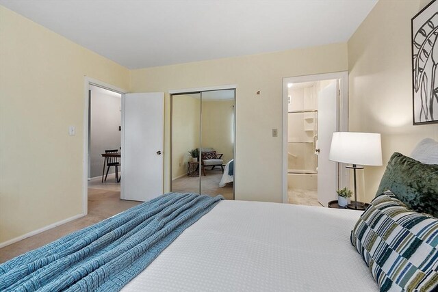 carpeted bedroom with a closet, baseboards, and ensuite bathroom