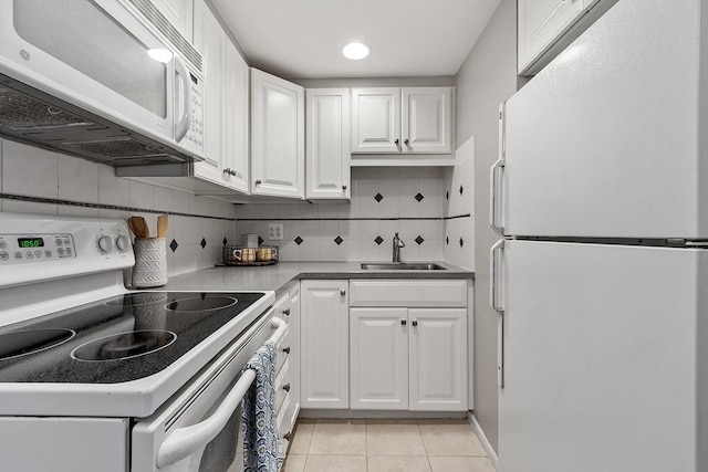 kitchen with white appliances, a sink, white cabinets, and light tile patterned floors