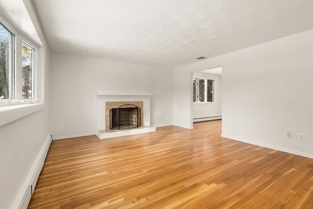 unfurnished living room with light hardwood / wood-style flooring, a high end fireplace, and baseboard heating