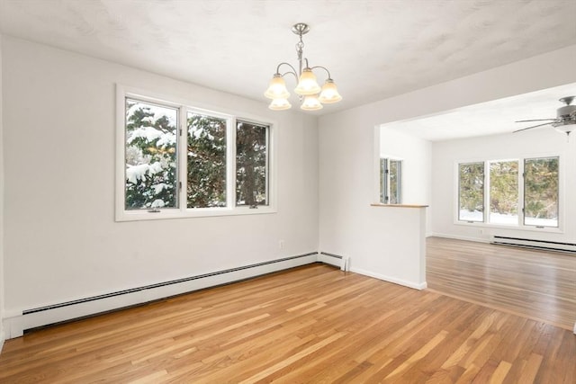 spare room featuring ceiling fan with notable chandelier, baseboard heating, and light hardwood / wood-style flooring