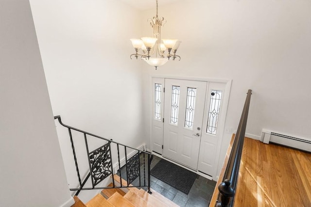 foyer with hardwood / wood-style flooring, a baseboard heating unit, and a notable chandelier