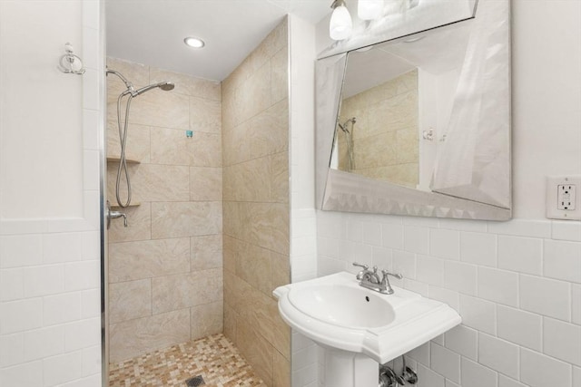 bathroom with sink, tile walls, and a tile shower