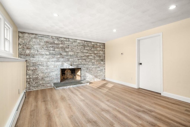 unfurnished living room with a baseboard heating unit, a fireplace, and light wood-type flooring