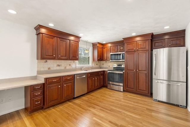 kitchen featuring sink, hanging light fixtures, stainless steel appliances, light hardwood / wood-style floors, and backsplash