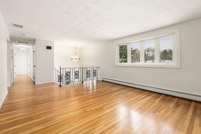 unfurnished room with hardwood / wood-style floors, a chandelier, and baseboard heating