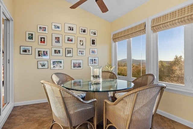 dining area featuring dark tile patterned flooring, ceiling fan, a mountain view, and lofted ceiling