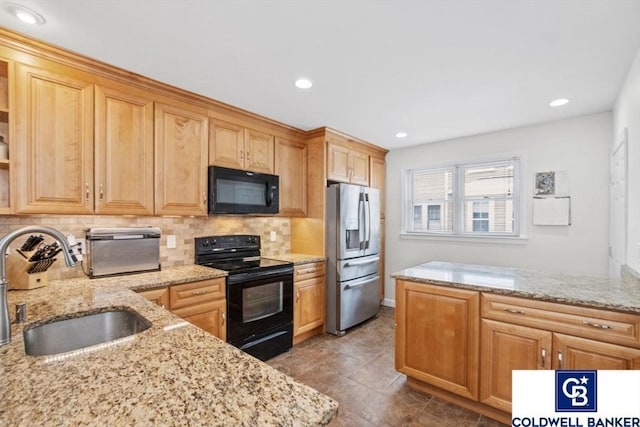 kitchen featuring tasteful backsplash, a sink, black appliances, and light stone countertops