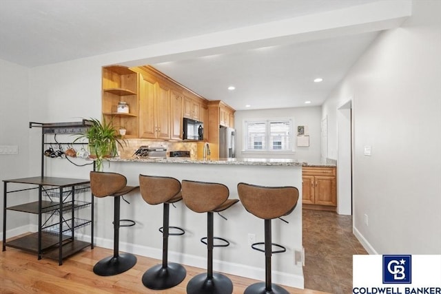 kitchen featuring black microwave, light stone counters, stainless steel fridge with ice dispenser, decorative backsplash, and open shelves