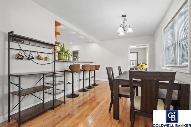 dining space with a chandelier, light wood-style flooring, and baseboards