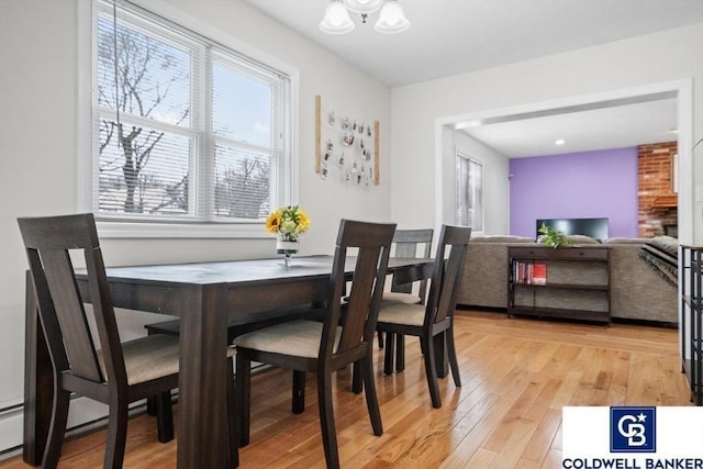 dining area featuring light wood finished floors, a baseboard radiator, and an inviting chandelier