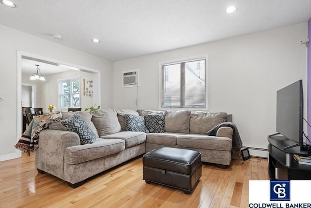 living room featuring a wealth of natural light, a baseboard radiator, a notable chandelier, and light wood finished floors