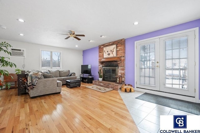 living area with recessed lighting, a fireplace, wood finished floors, an AC wall unit, and french doors