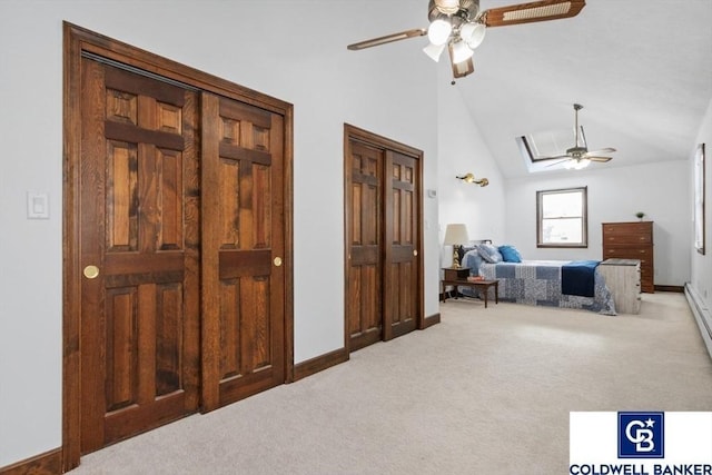 carpeted bedroom featuring vaulted ceiling with skylight, baseboards, ceiling fan, and multiple closets