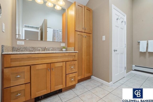 bathroom with a baseboard radiator, tile patterned flooring, vanity, and baseboards