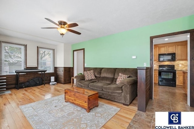 living room with ceiling fan, light wood-style flooring, and wainscoting